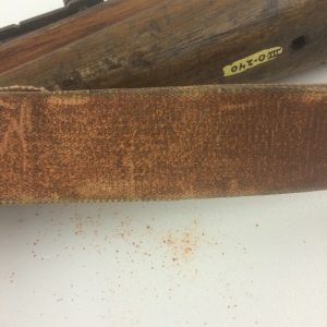 The strap of the rifle is actively flaking an orange powder.  This material will need to be characterized and stabilized before it can go on display.